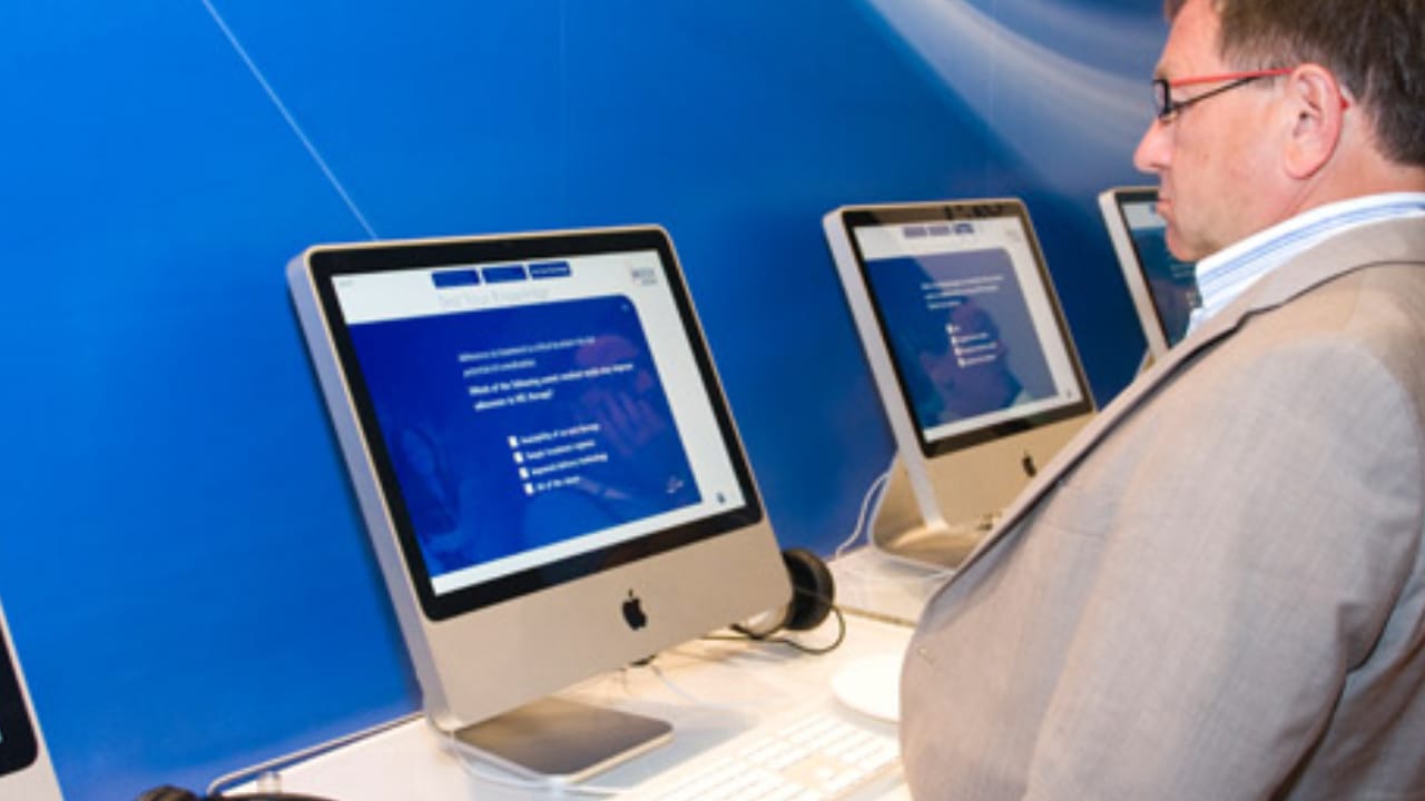 A visitor using the Merck Serono data kiosk on an iMac